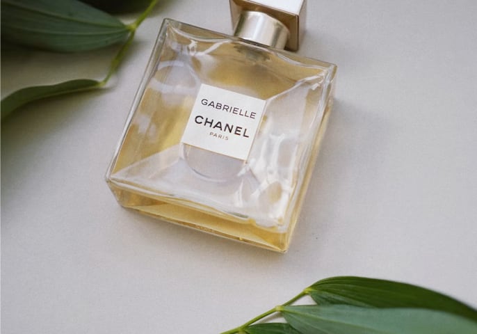 Chanel perfume on the table, two green leaves